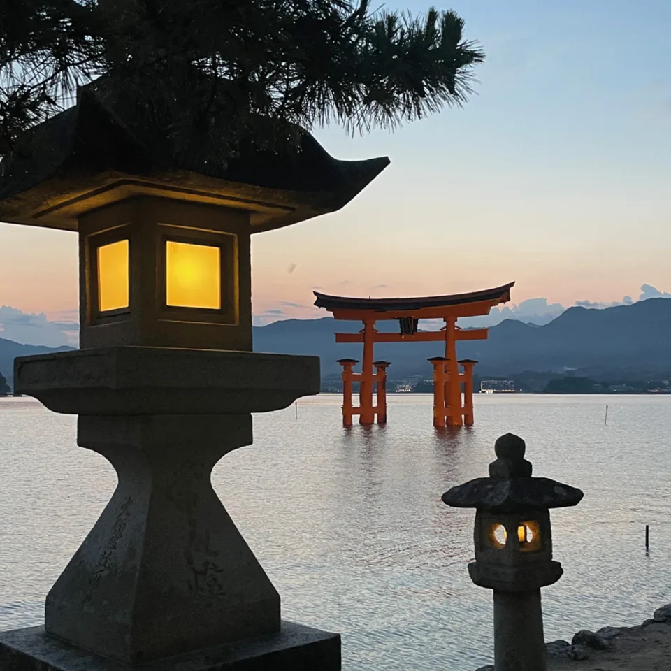 A stone lantern and the torii gate at Miyajima at dusk
